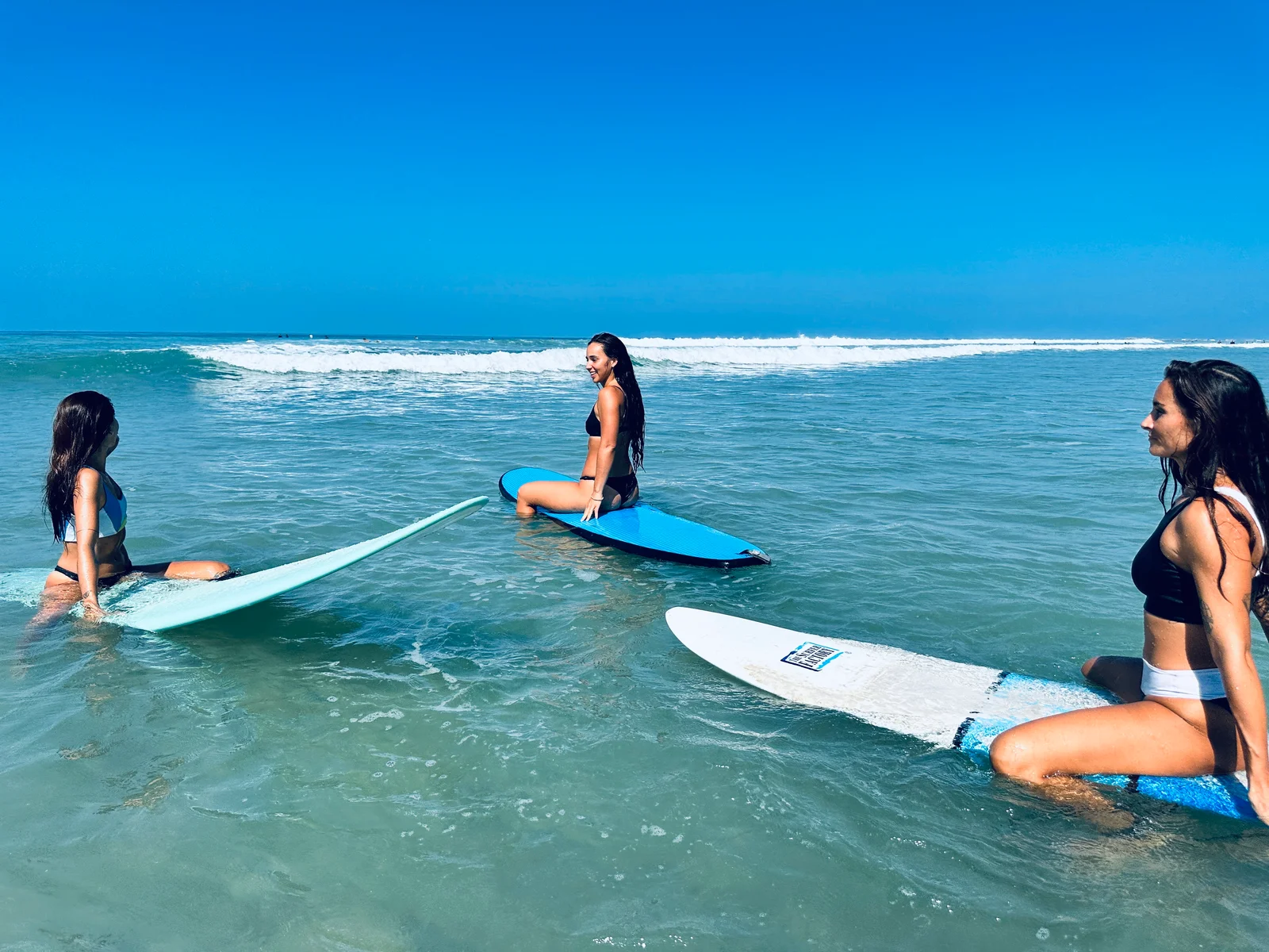 Surfers sitting on their boards in the water at Playa Guiones, from NSI’s Spanish and Surf program.